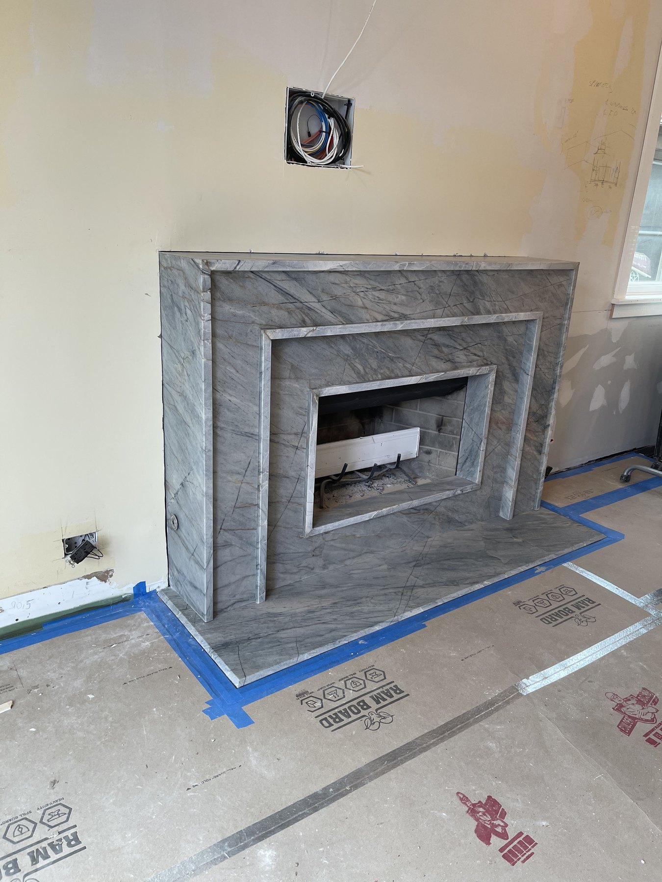 Gray stone fireplace surround being fitted during construction
