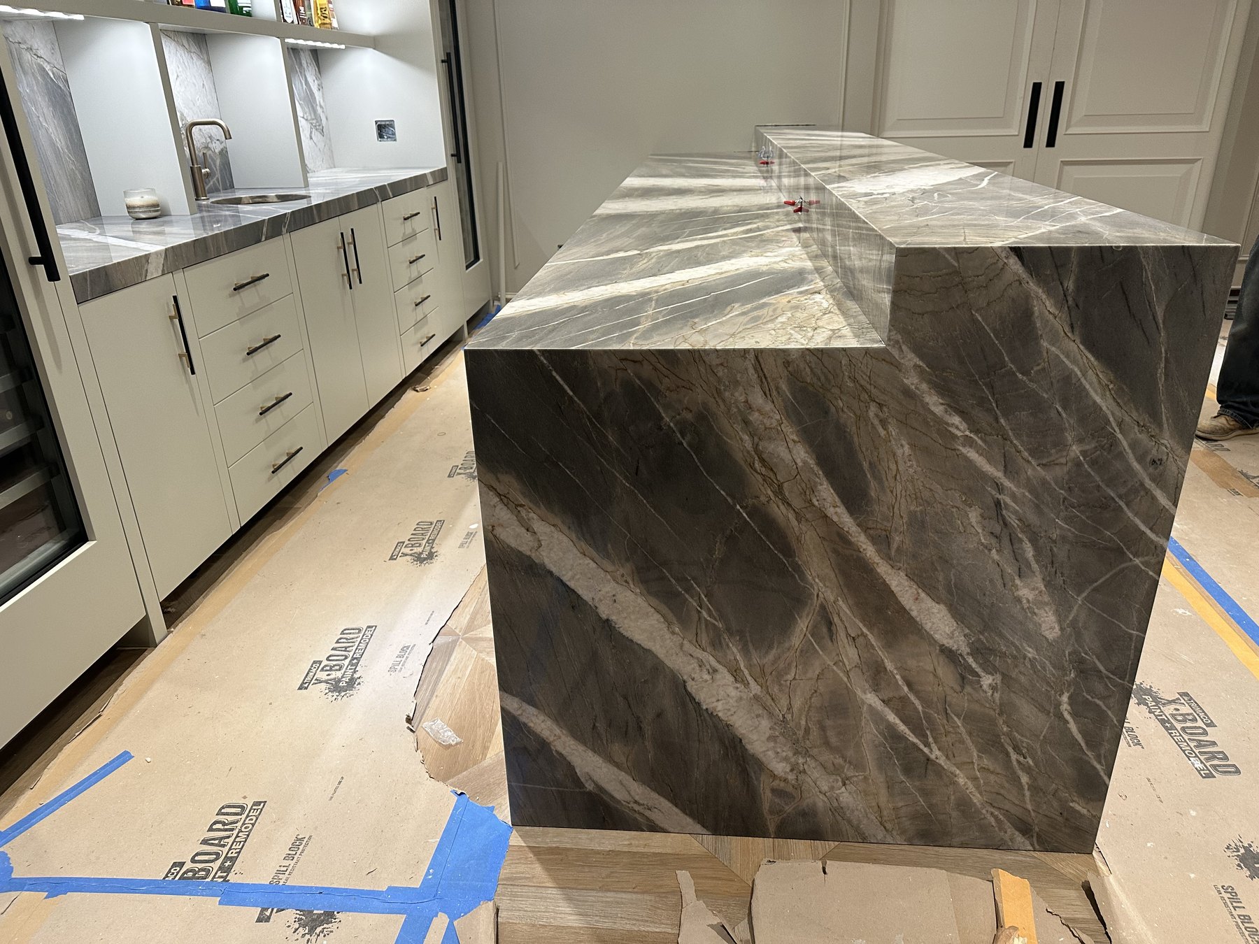 Layered gray stone island with mitered waterfall panels during installation
