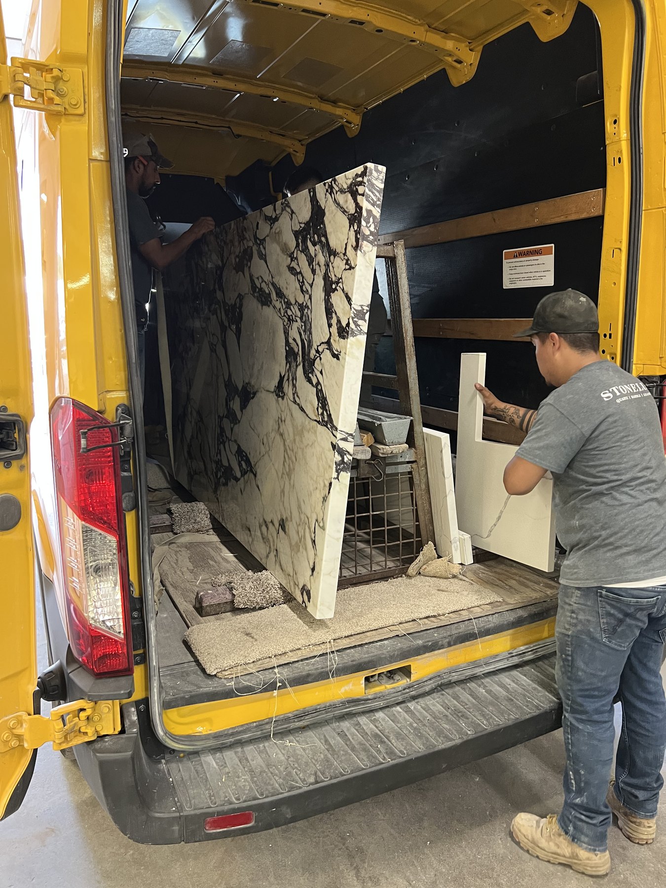 STONELUX installers unloading a dramatic stone slab from the company van