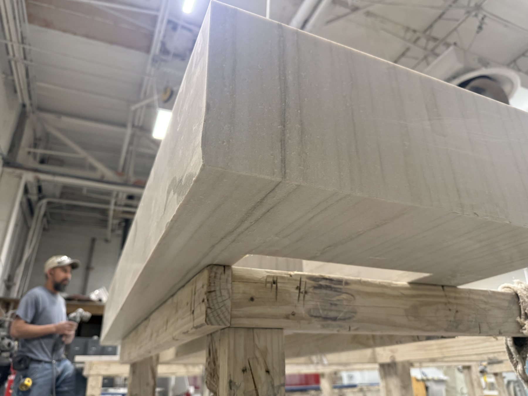 STONELUX fabricator inspecting a mitered waterfall stone edge in the shop