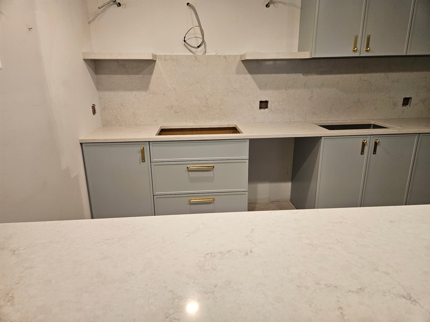 Light stone countertops and backsplash with pale gray cabinetry