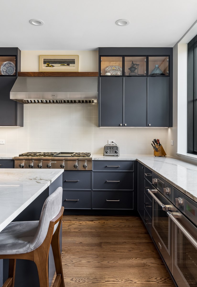 Finished navy kitchen with bright natural-stone countertops and professional appliances